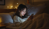 A_young_Korean_woman_looking_at_her_phone_in_bed_a-1737094912317.png